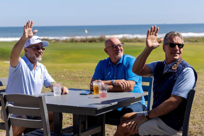 Three gentlemen having a drink by the coast